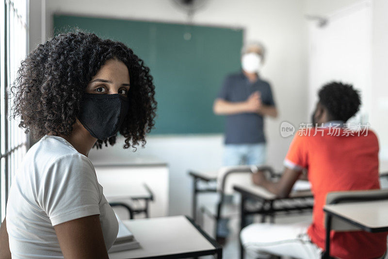 一个大学/高中学生戴着口罩在教室里的肖像